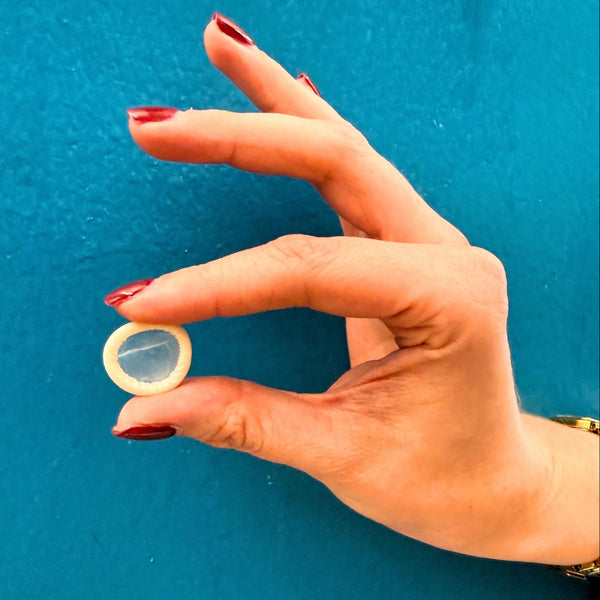 Hand holding a small round object against a blue background