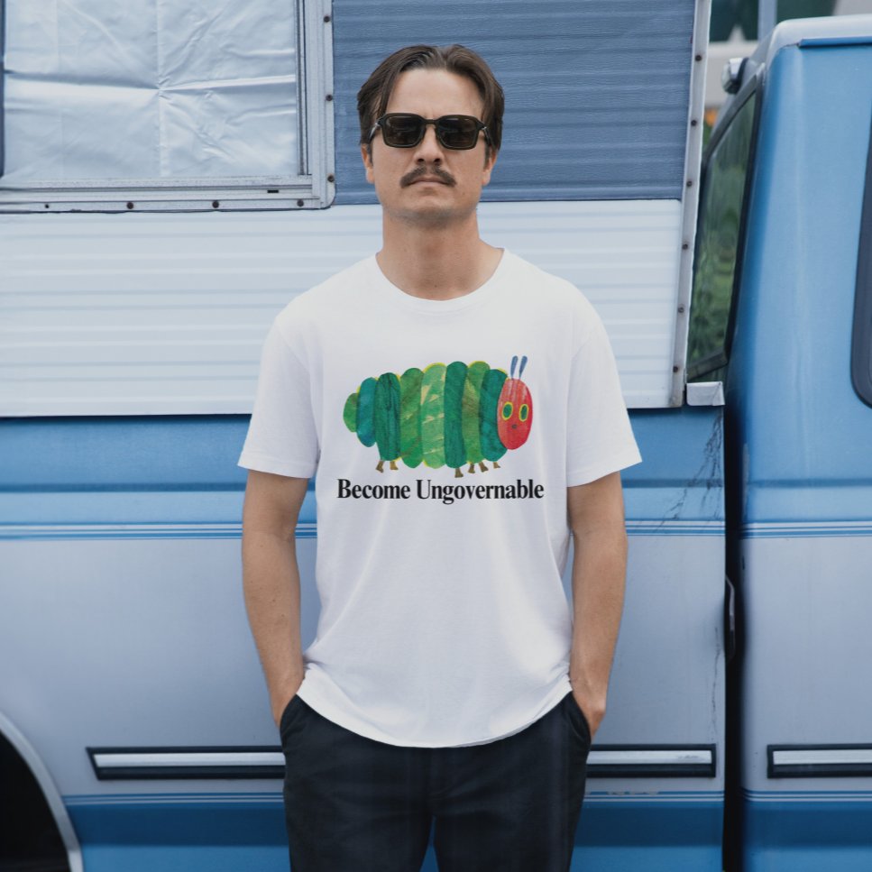 Man wearing a white t-shirt with a graphic design and text, standing in front of a blue van.